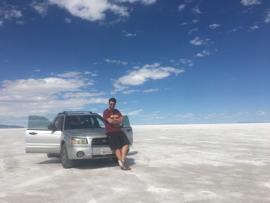 Man leaning against silver Toyota in the middle of a salt flat