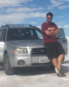 Man leaning against Silver Toyota Forester in a salt flat