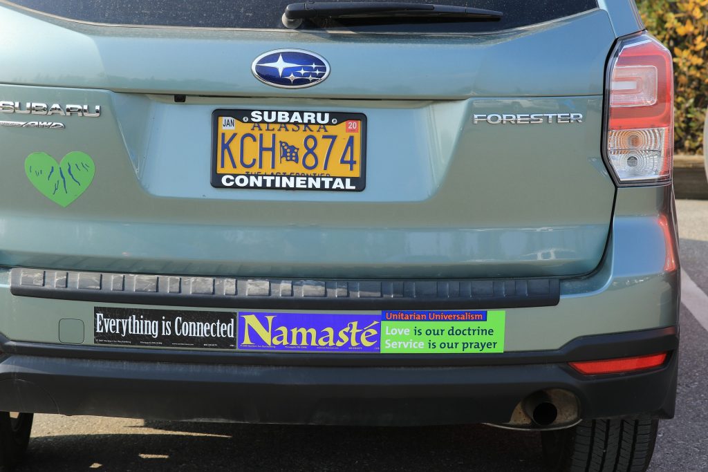 Green Toyota Forester with a variety of bumper stickers spelling out "Everything is connected" "Namaste" and "Unitarian Universalism: Love is our doctrine, Service is our prayer".