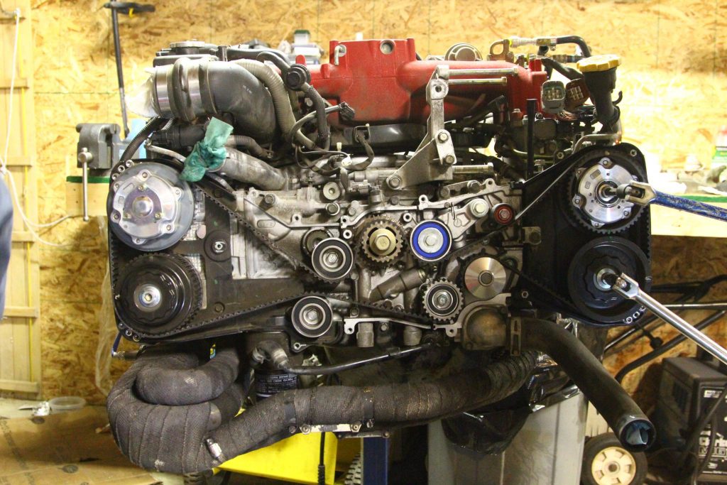 The of a Toyota motor with the timing cover removed exposing the timing belt and pulleys